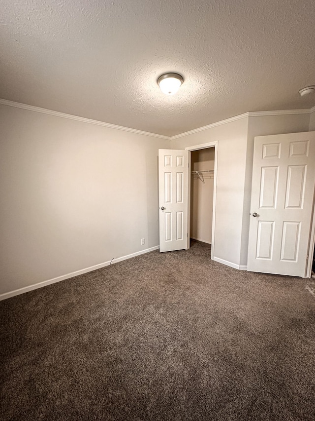 unfurnished bedroom featuring a textured ceiling, dark colored carpet, and ornamental molding