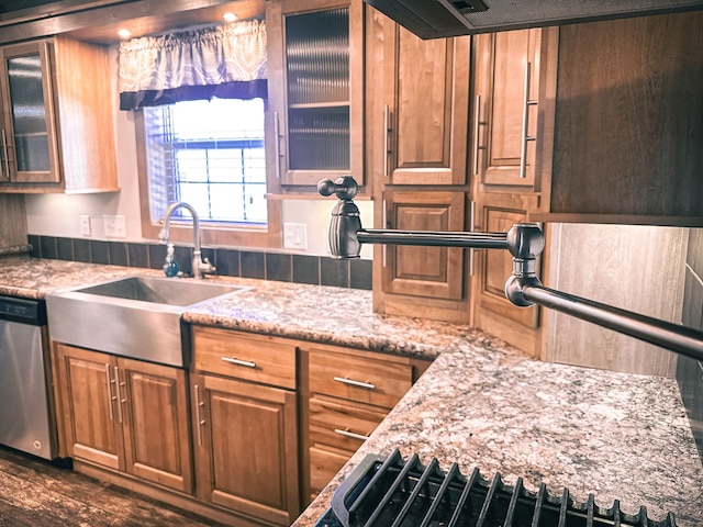 kitchen featuring glass insert cabinets, light stone countertops, dishwasher, and a sink