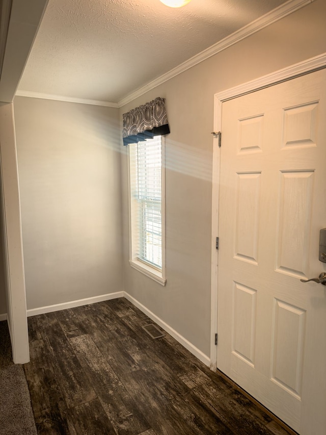 entrance foyer featuring dark wood-type flooring, baseboards, ornamental molding, and a textured ceiling