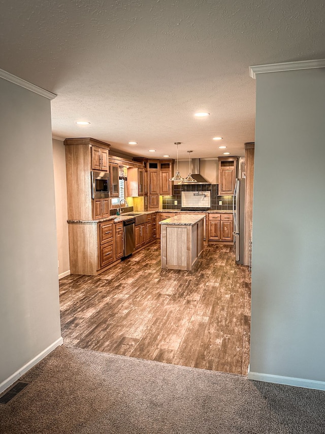 kitchen featuring ornamental molding, recessed lighting, a center island, brown cabinets, and appliances with stainless steel finishes