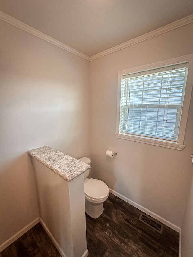bathroom with visible vents, baseboards, ornamental molding, toilet, and wood finished floors