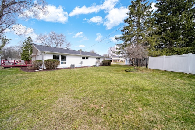 view of yard featuring a wooden deck, fence, and central AC