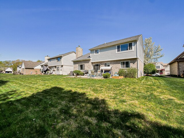 rear view of house featuring a lawn, a patio, a residential view, and brick siding