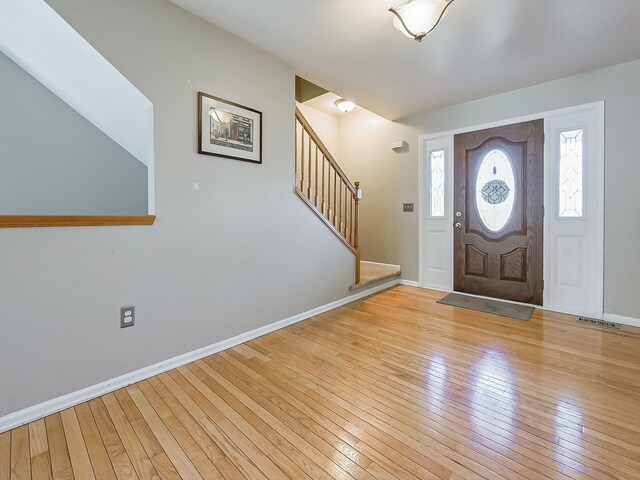 foyer with baseboards, visible vents, stairway, and light wood-style floors