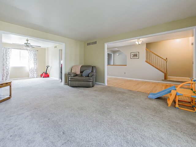 sitting room with carpet, a ceiling fan, baseboards, visible vents, and stairway