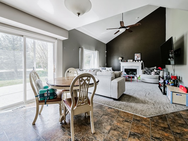 dining space with stone finish flooring, ceiling fan, visible vents, and vaulted ceiling