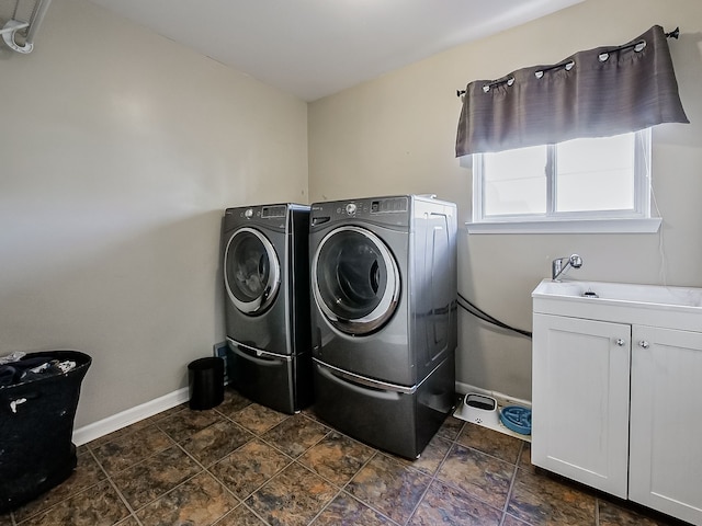 laundry room with baseboards, stone finish flooring, cabinet space, and washing machine and dryer