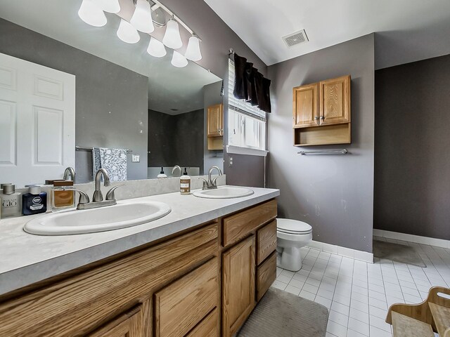 bathroom featuring toilet, visible vents, a sink, and tile patterned flooring