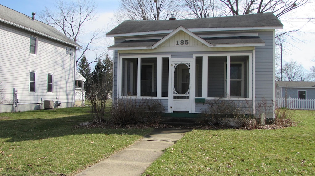 185 Henry St, Coldwater, MI 49036 - view of front of house featuring cooling unit, a front yard, and a sunroom