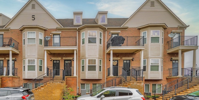 townhome / multi-family property with brick siding, roof with shingles, central air condition unit, and stairs