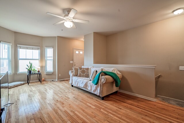 living area featuring a ceiling fan, baseboards, and wood-type flooring