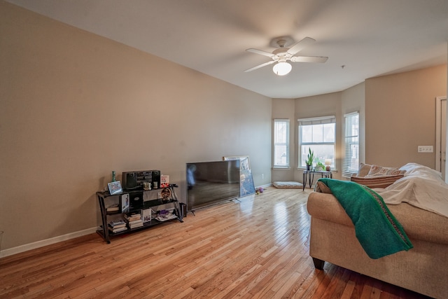 living room with ceiling fan, light wood finished floors, and baseboards