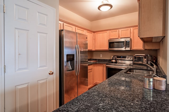 kitchen featuring a sink, light brown cabinetry, dark stone countertops, and stainless steel appliances