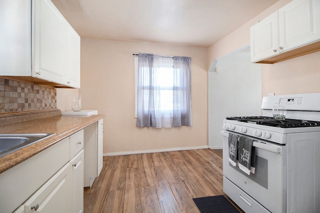 26410 Beverly Rd, Taylor, MI 48180 - kitchen with white gas stove, light wood finished floors, backsplash, and white cabinetry