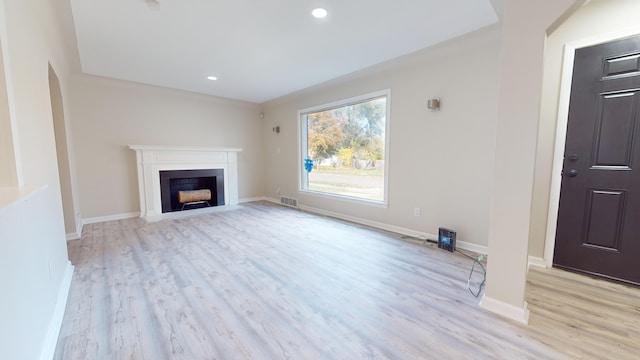 unfurnished living room with visible vents, a fireplace with flush hearth, baseboards, and wood finished floors