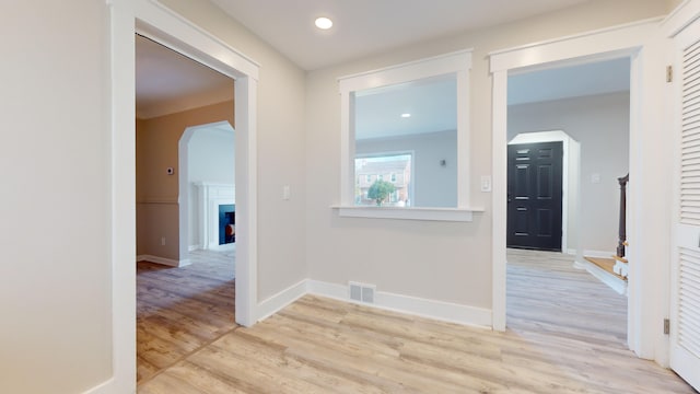 corridor featuring light wood-style flooring, visible vents, baseboards, recessed lighting, and arched walkways