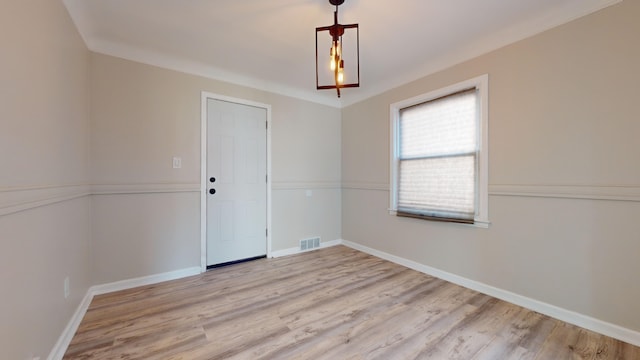 unfurnished room featuring baseboards, visible vents, and wood finished floors