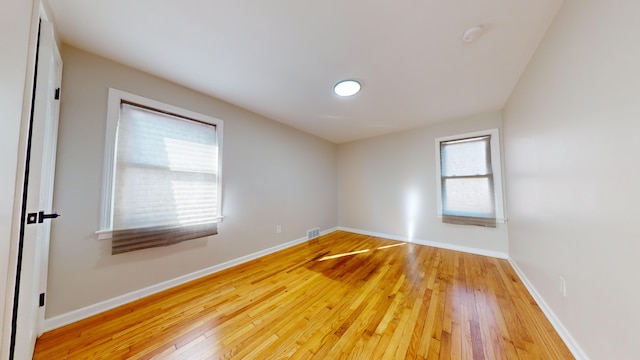 spare room with baseboards, visible vents, and light wood finished floors