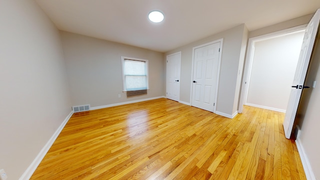 unfurnished bedroom featuring baseboards, visible vents, and light wood-type flooring