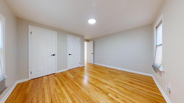 unfurnished bedroom with baseboards and light wood-style flooring
