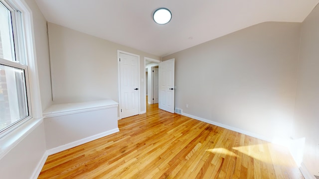 unfurnished room featuring visible vents, baseboards, vaulted ceiling, and wood finished floors
