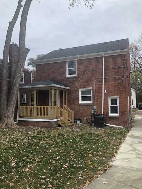 back of property featuring a lawn, brick siding, and a porch