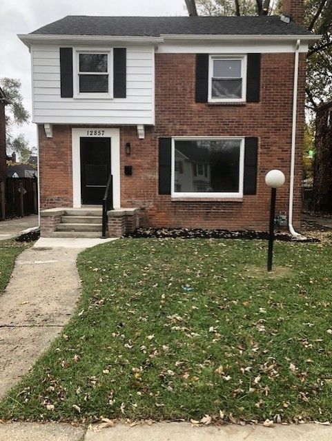 view of front of house with brick siding, a chimney, a front lawn, and entry steps