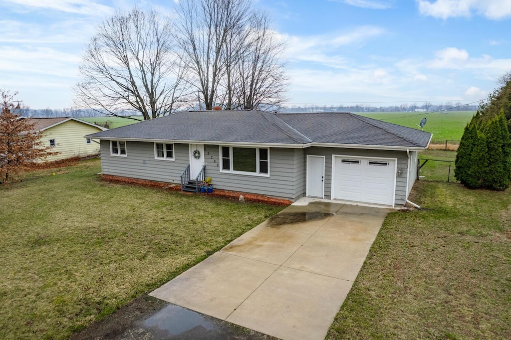 single story home with concrete driveway, roof with shingles, an attached garage, entry steps, and a front yard