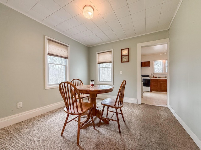dining space featuring light carpet and baseboards