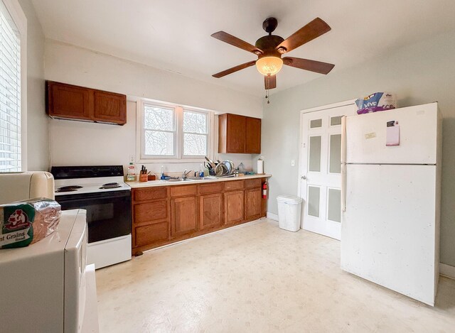 kitchen with light countertops, electric range oven, freestanding refrigerator, brown cabinetry, and light floors