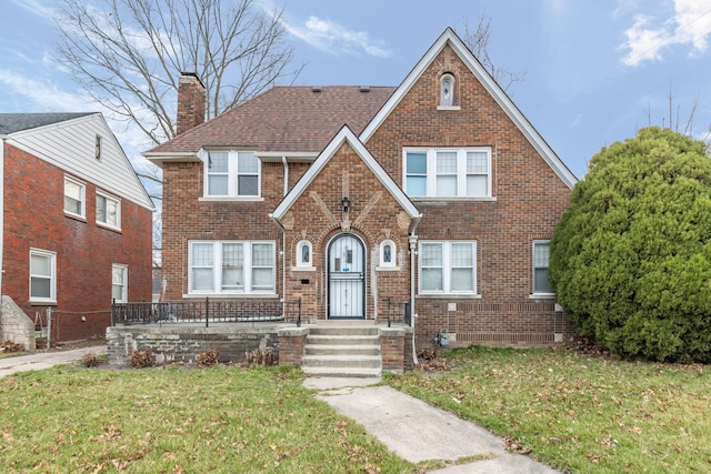 5959 Three Mile Dr, Detroit, MI 48224 - tudor home with a chimney, a front yard, and brick siding