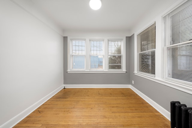 5959 Three Mile Dr, Detroit, MI 48224 - empty room with radiator heating unit, light wood-style floors, and baseboards