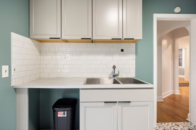 5959 Three Mile Dr, Detroit, MI 48224 - kitchen featuring light countertops, decorative backsplash, a sink, arched walkways, and wood finished floors