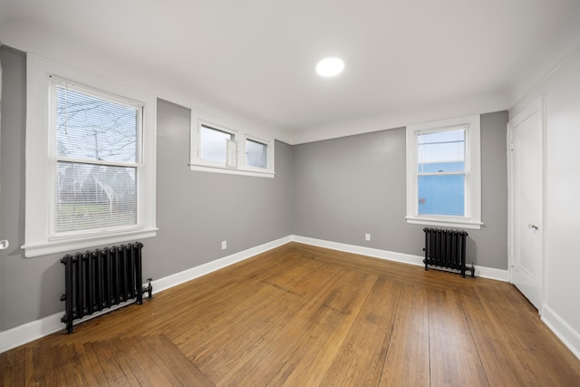 5959 Three Mile Dr, Detroit, MI 48224 - empty room featuring baseboards, plenty of natural light, radiator heating unit, and hardwood / wood-style flooring