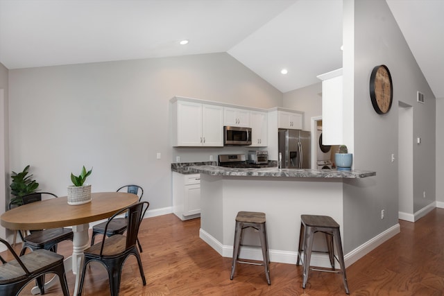 33172 Swallow Dr, Rockwood, MI 48173 - kitchen featuring wood finished floors, a breakfast bar area, white cabinets, a peninsula, and appliances with stainless steel finishes