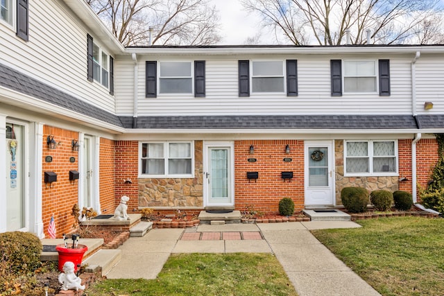 multi unit property featuring stone siding and a shingled roof