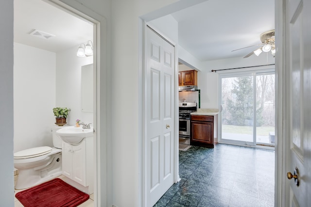 bathroom with toilet, vanity, a ceiling fan, visible vents, and decorative backsplash