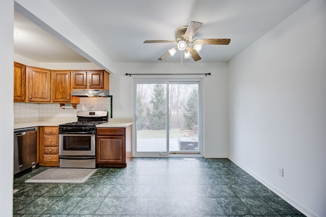 kitchen featuring under cabinet range hood, backsplash, a ceiling fan, appliances with stainless steel finishes, and brown cabinetry