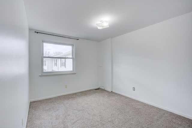 spare room with baseboards, visible vents, and carpet