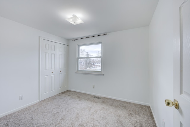 unfurnished bedroom featuring baseboards, visible vents, a closet, and carpet flooring