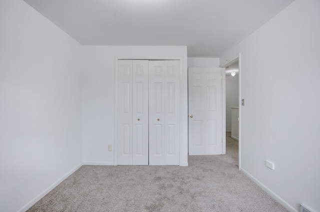 unfurnished bedroom featuring a closet, carpet floors, visible vents, and baseboards