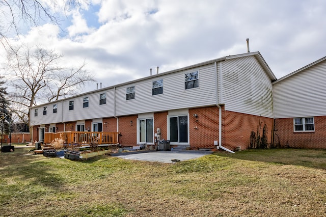 back of property featuring brick siding, a patio, a garden, and a yard