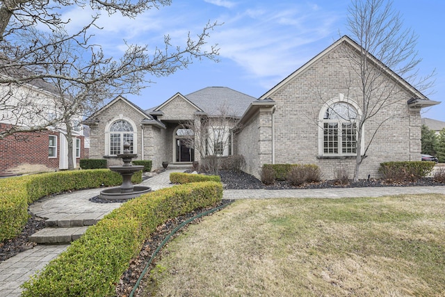 french country home featuring brick siding and a front yard
