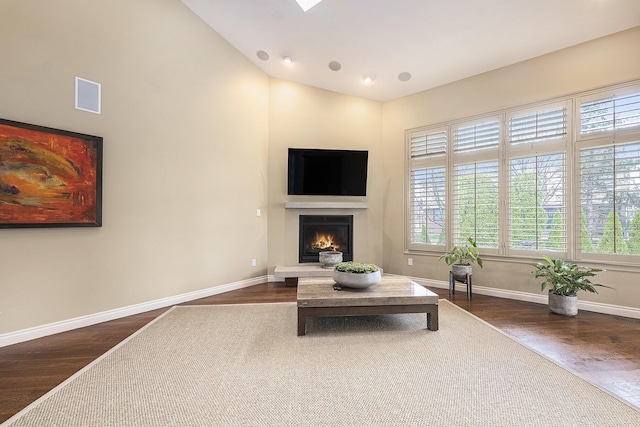 living room with a lit fireplace, dark wood-style floors, visible vents, and vaulted ceiling