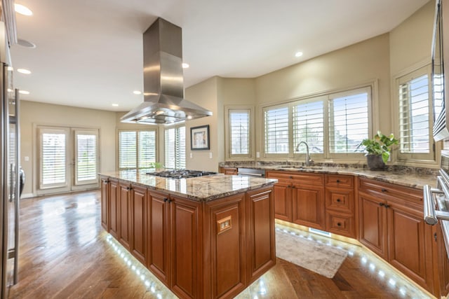 kitchen with a center island, a sink, island range hood, light wood-style floors, and brown cabinetry