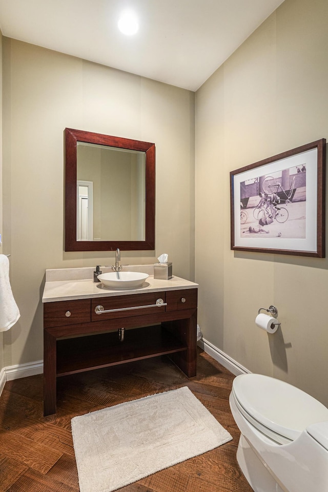 bathroom with toilet, vanity, and baseboards
