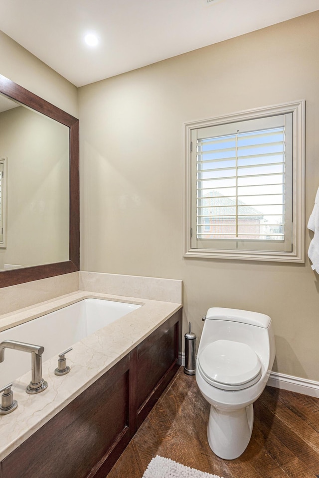 half bath with baseboards, wood finished floors, and toilet