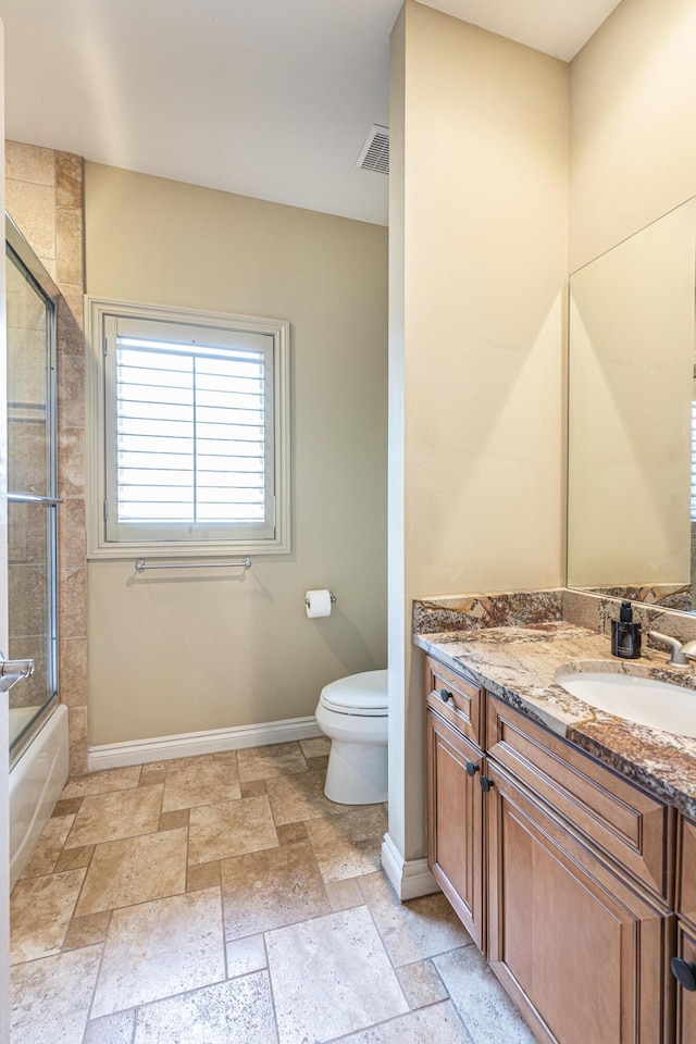 full bathroom with vanity, stone tile floors, toilet, baseboards, and visible vents