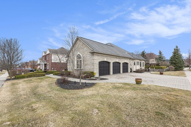 view of property exterior with brick siding, decorative driveway, a garage, and a yard