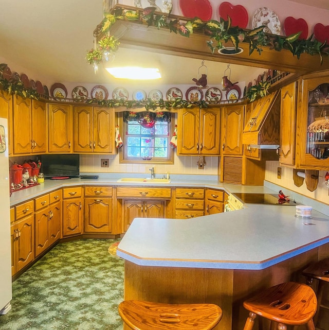 kitchen featuring light countertops, brown cabinets, a sink, and a breakfast bar area